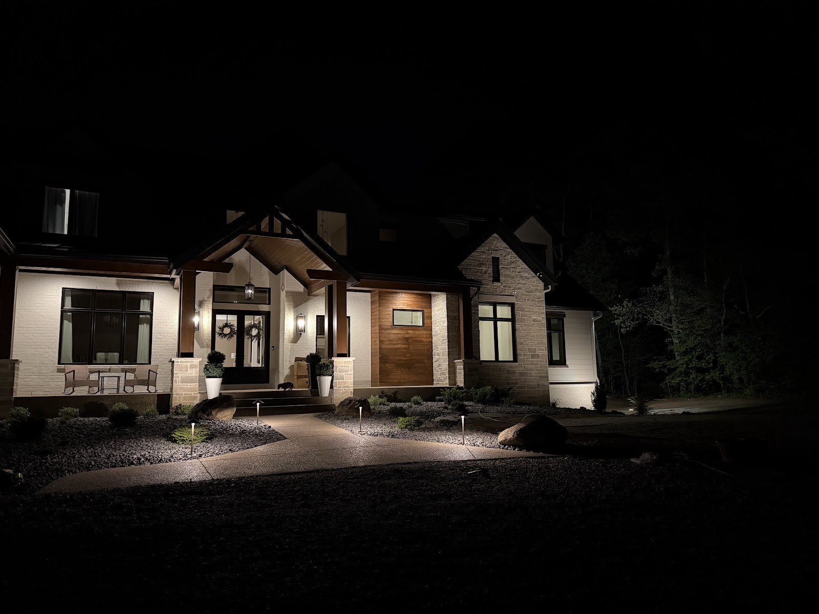 Night shot of a custom home with new path and accent landscape lighting along rock beds and the entry walk.