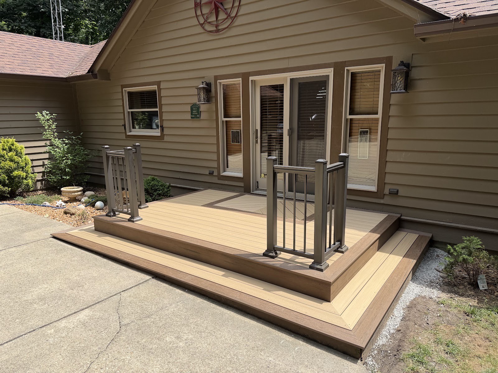 Finished two-tone composite front porch deck with picture-frame border and gray railings on a tan ranch home.